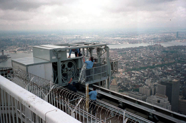 Techniker beschäftigen sich in schwindelerregender Höhe mit einer der Fenster-Reinigungsmaschinen, die vom Dach des World Trade Centers aus operieren.
