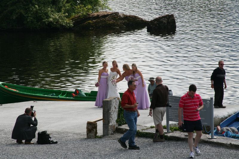 Eine junge Braut und ihre Brautjungfern& posieren für ein Foto vor dem Ross Castle am Ufer des Lough Leane vor.