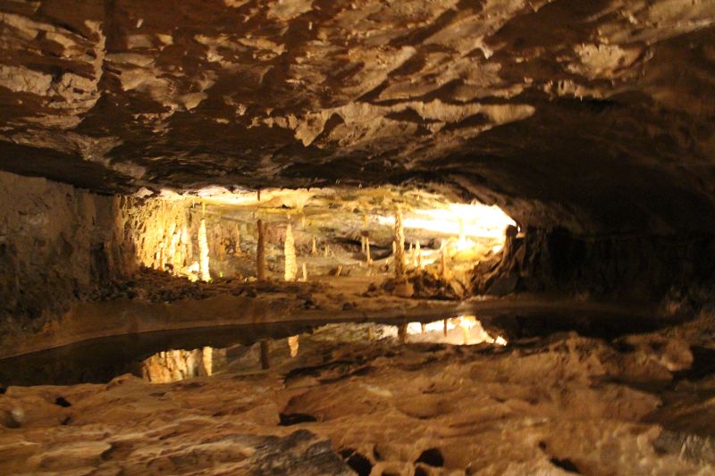 Larger underground basin with water. The cave ceiling is relected in the water.