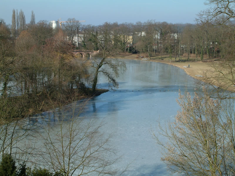 View from the look-out tower in the centre of Schönbusch Park over the frozen lake and Red Bridge