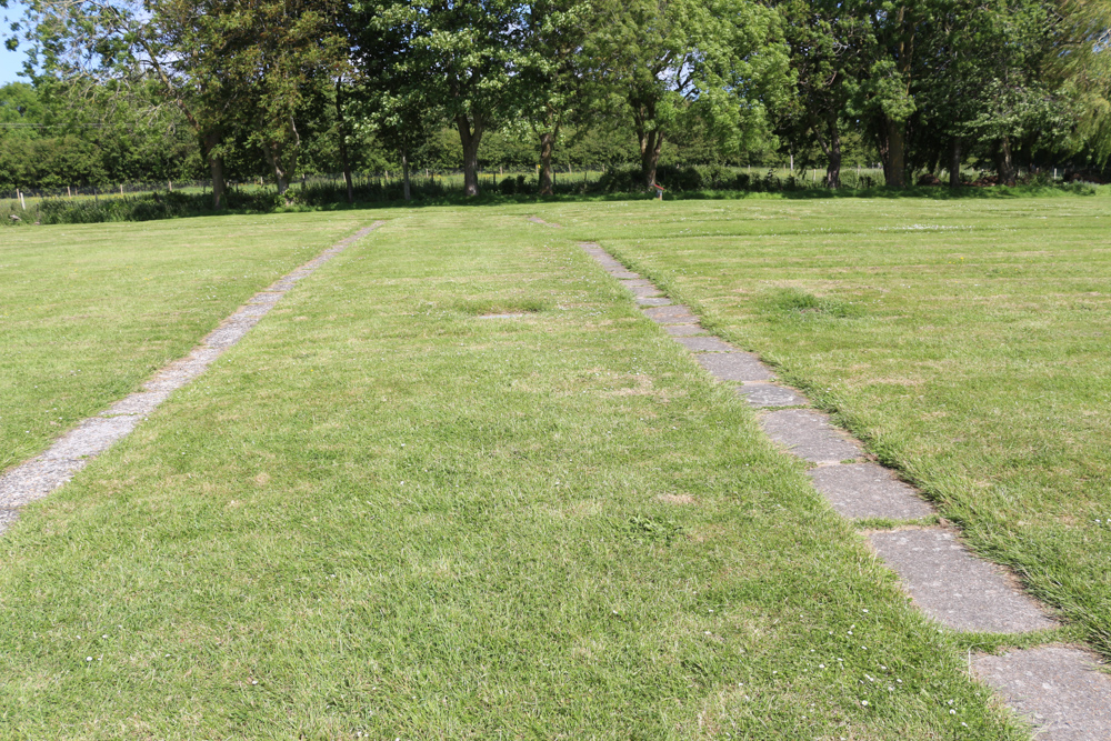 Stone lines highlight the former building walls in the grass around the museum building