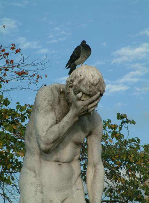 Statue in einer Geste der Verzweiflung. Die Taube auf dem Kopf lässt die Skulptur nicht gerade glücklicher aussehen.