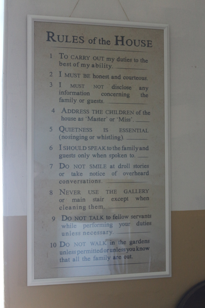 Ein Schild an der Wand zeigt die Hausregeln des Culzean Castle. Eine recht klare und harsche Anweisung an alle Mitarbeiter.
Zur Erfüllung meiner Pflichten nach besten Kräften muss ich ehrlich und zuvorkommend sein. Ich darf keine Informationen über die Familie oder ihre Gäste offenlegen. Die Kinder des Hauses sind mit 'Master' oder 'Miss' anzusprechen. Stille ist unbedingt notwendig (kein Gesang oder Pfeifen). Ich soll mit Familienmitgliedern oder Gästen nur sprechen wenn ich angesprochen wurde. Die Galerie oder die Haupttreppe dürfen nie betreten werden, außer um sie zu reinigen. Sprechen Sie während der Arbeit nur wenn nötig mit anderen Bediensteten. Betreten Sie den Garten nur mit Erlaubnis oder wenn Sie wissen, dass die gesamte Familie abwesend ist.