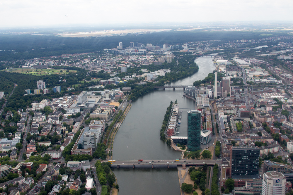 View from a helicopter over Frankfurt: Friedensbrücke and West Harbor Frankfurt. In the background the city district Niederrad and Frankfurt Airport.