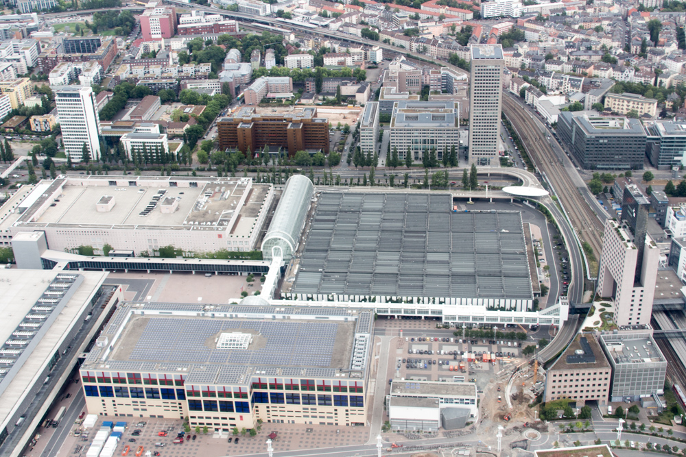 Blick aus einem Hubschrauber über Frankfurt am Main: Die Frankfurter Messe mit den Hallen 8, 9 und 10. Hinter der Theodor-Heuss-Allee befinden sich eine ganze Reihe von Büro- und Wohngebäuden.