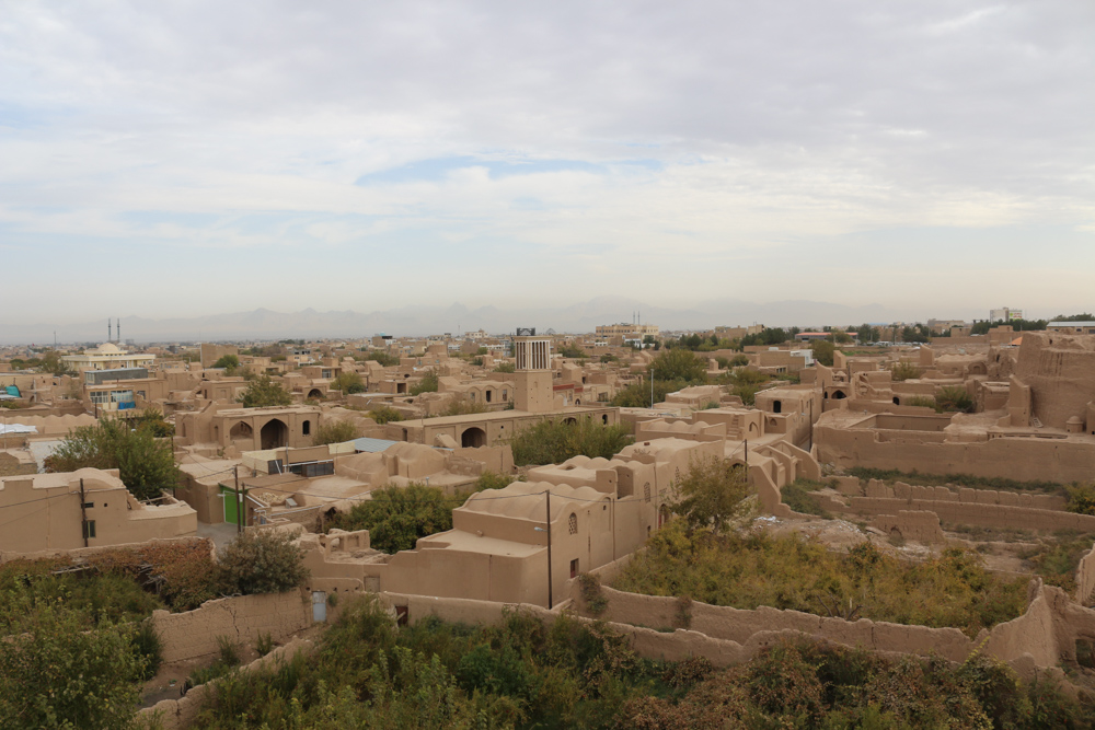 Blick von der Zitadelle über die aus Lehm erbaute Wüstenstadt Meybod und die dahinter liegende Gebirgskette.