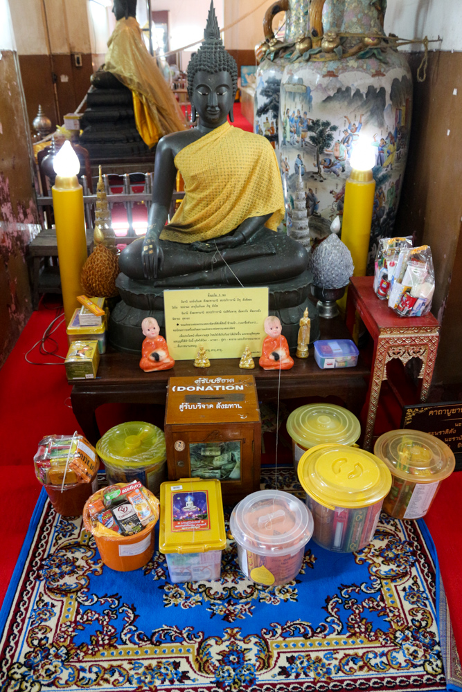 Small altar with donations in the Wihan Phramongkhon Bophit temple of Ayutthaya