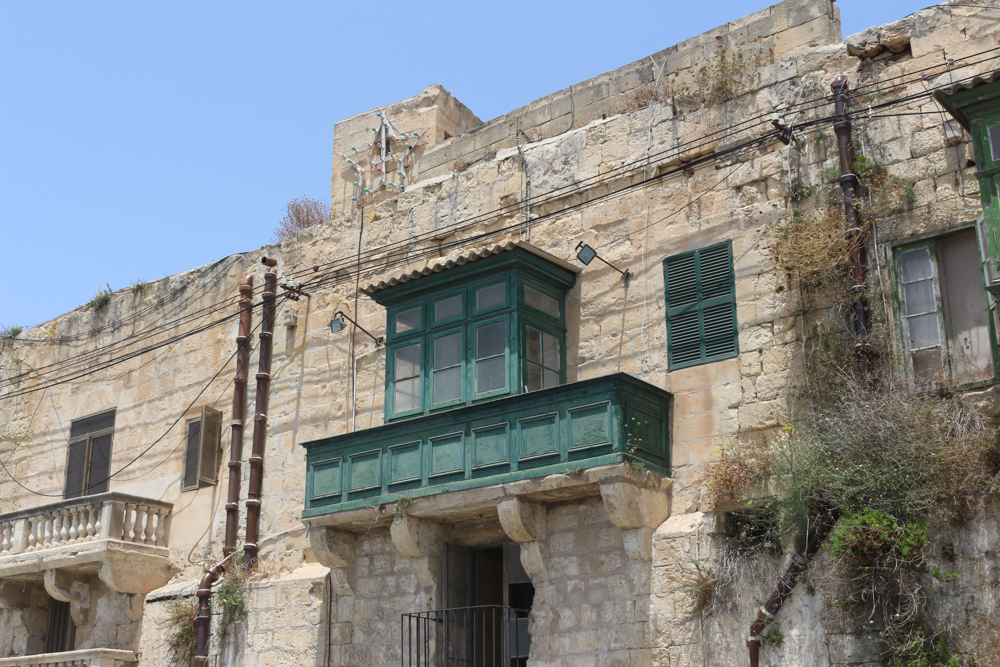 Cumbling Maltese house in Valletta with wooden green enclosed balcony