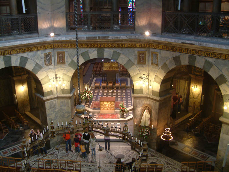 Blick von der Empore des Kaiserthrons hinab zum Altar des Doms zu Aachen. In der Mitte der gewaltige Barbarossaleuchter.