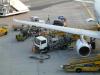 A plane is refuelled while workers are loading luggage into the cargo hold