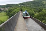 Narrowboat on the Pontcysyllte Aqueduct. People are walking on the side walkway built for the horses.