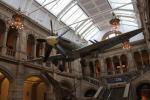 West Court hall of Kelvingrove Museum with a Spitfire LA198 hanging above an elephant, a giraffe, etc.